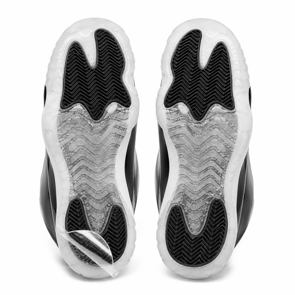 Pair of sneaker outsoles with Ultimate Sole Protectors clear film applied, one corner lifted to show the film peeling away cleanly
